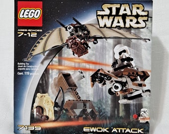 May include: A Lego Star Wars Ewok Attack set with 119 pieces. The box features a brown and white speeder bike, a brown and tan Ewok speeder, and a brown and tan Ewok with a bow and arrow. The box also features the text "LEGO Star Wars Ewok Attack" and "7139".