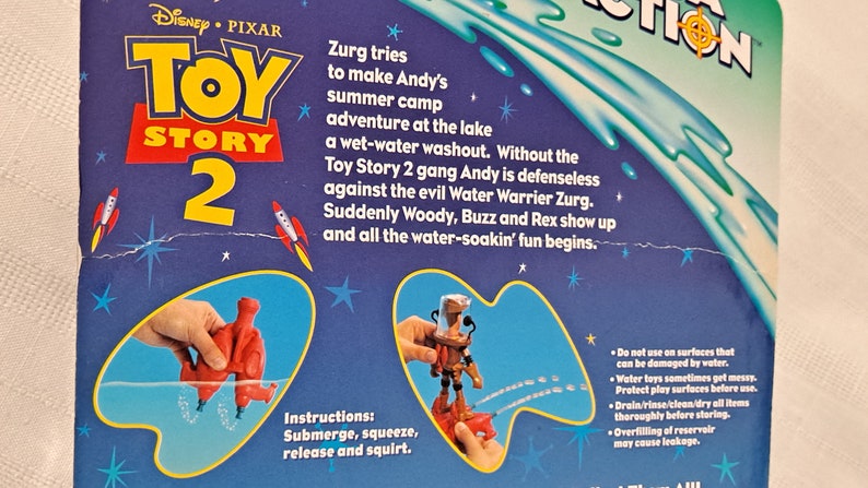 Pode incluir: Brinquedos de &aacute;gua Toy Story 2 com Woody e Buzz Lightyear. Os brinquedos s&atilde;o vermelhos e laranja e s&atilde;o mostrados submersos na &aacute;gua. A embalagem tem um fundo azul com estrelas e o logotipo do Toy Story 2.