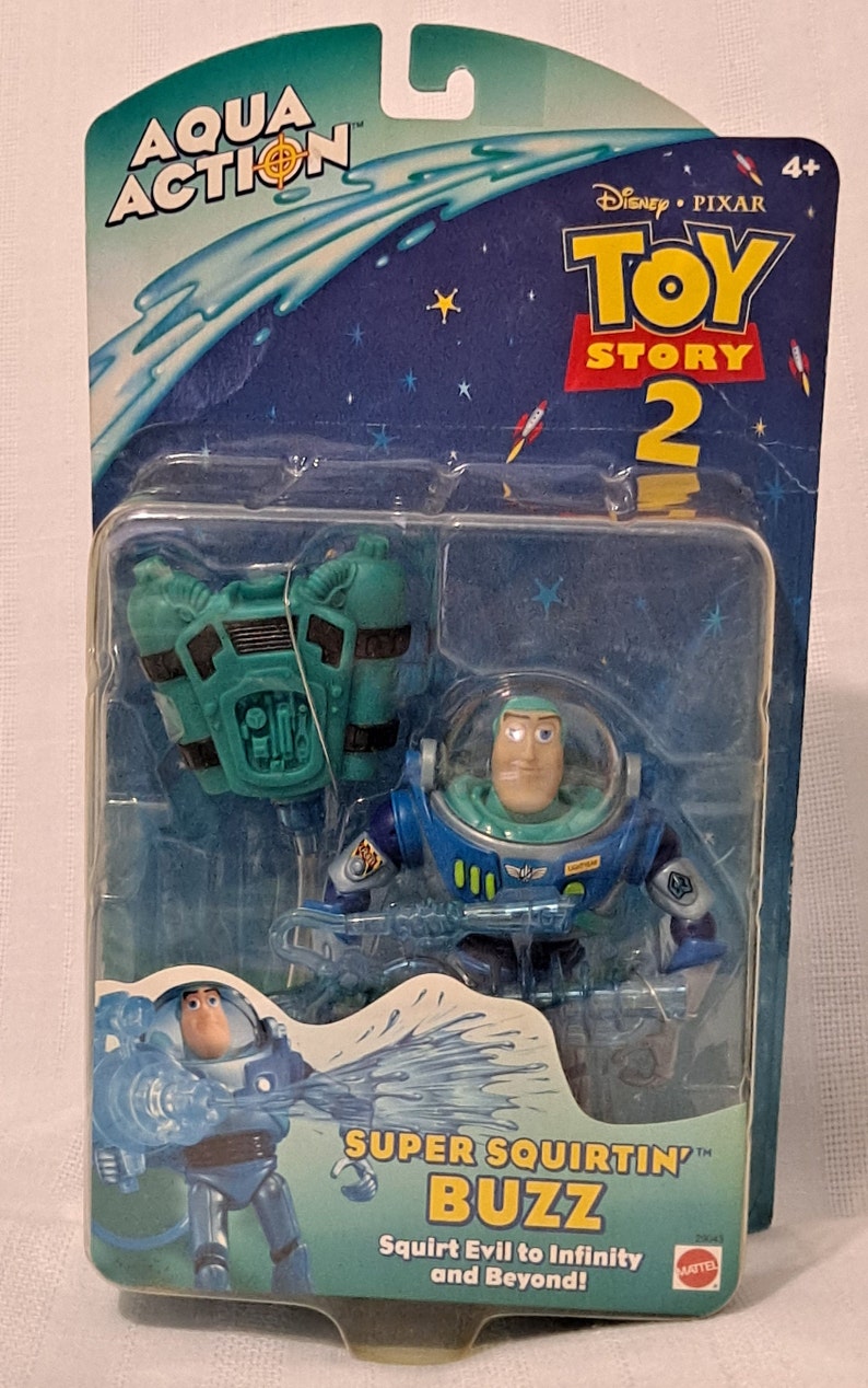 Peut inclure: Une figurine d'action en plastique bleue et verte de Buzz l'&Eacute;clair de Toy Story 2. La figurine tient un pistolet &agrave; eau et porte un sac &agrave; dos. L'emballage est bleu et vert avec les mots "Aqua Action" et "Super Squirtin' Buzz" dessus.