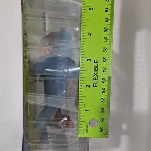 May include: A blue and brown plastic toy shark figure in clear plastic packaging. The packaging is labelled "Flexible" and has a ruler on the side. The ruler measures 76.2 cm.