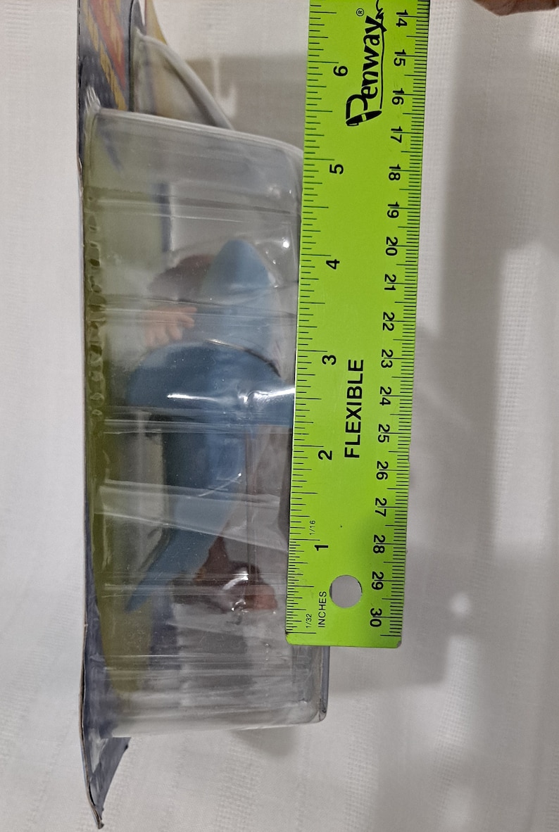 May include: A blue and brown plastic toy shark figure in clear plastic packaging. The packaging is labelled "Flexible" and has a ruler on the side. The ruler measures 76.2 cm.