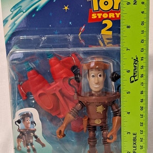 Pode incluir: Figura de a&ccedil;&atilde;o Toy Story 2 Water Patrol Woody com um esguicho de &aacute;gua vermelho. A figura est&aacute; usando um traje espacial marrom com um distintivo de estrela de xerife. A figura est&aacute; segurando uma pistola de &aacute;gua. A embalagem diz "Quick Draw Squirter!"