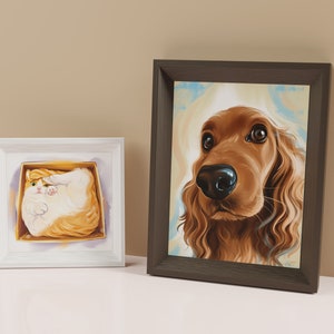 May include: Two framed pet portraits, one of a cat and one of a dog. The cat portrait is in a white frame and the dog portrait is in a brown frame. The cat is a white and orange tabby and is curled up in a box. The dog is a brown and white cocker spaniel and is looking directly at the viewer.