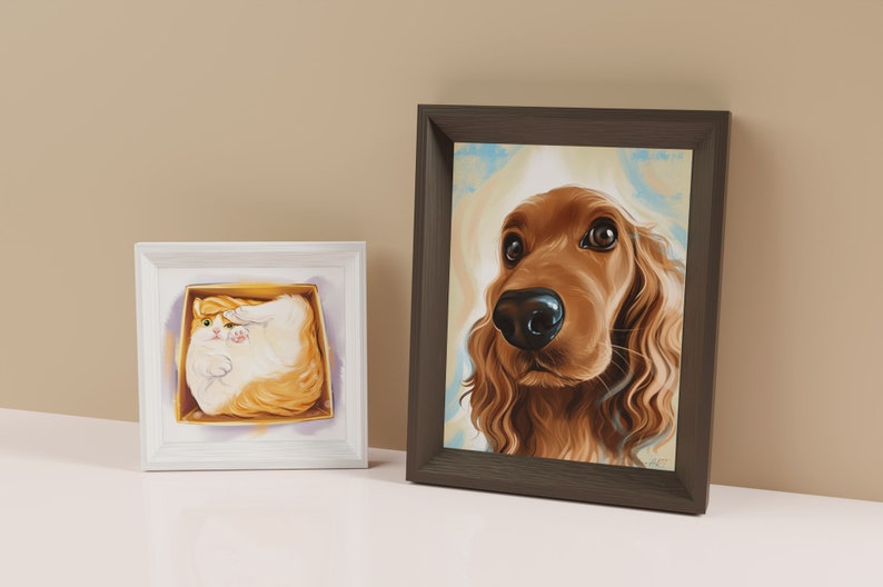 May include: Two framed pet portraits, one of a cat and one of a dog. The cat portrait is in a white frame and the dog portrait is in a brown frame. The cat is a white and orange tabby and is curled up in a box. The dog is a brown and white cocker spaniel and is looking directly at the viewer.