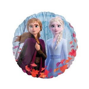 May include: A round foil balloon featuring a printed illustration of two characters, one with auburn hair in a purple coat and the other with platinum blonde hair in a light blue dress, set against a forest background with scattered red autumn leaves.