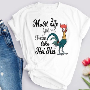 May include: White t-shirt with a graphic of a rooster with the text "Mom life got me feelin' like Hei Hei".
