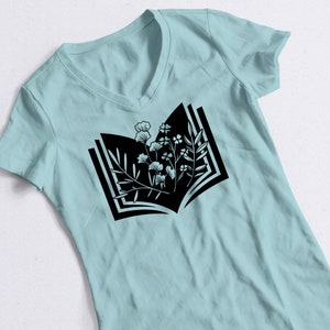 May include: A light blue t-shirt with a black graphic of an open book with flowers growing from the pages.