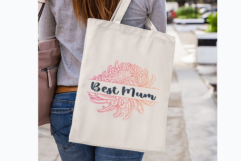 以下が含まれることがあります： 濃い青色の「Best Mum」の文字と、ピンクとオレンジの花柄が描かれた白いトートバッグです。