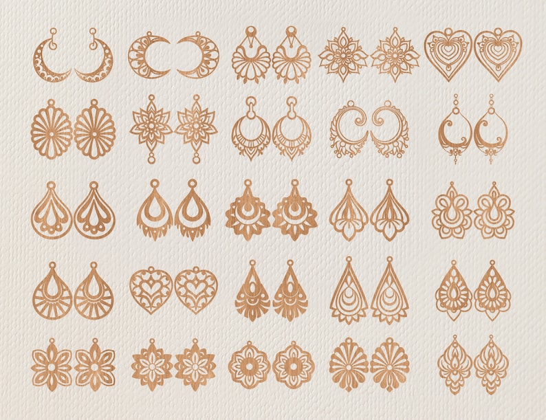 May include: A collection of various laser-cut earrings in a warm, metallic tone. Designs include crescent moons, floral patterns, teardrops, and hearts. The earrings are displayed on a neutral, textured background.