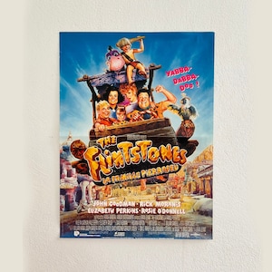 Può includere: Un poster del film "Gli Antenati" del 1994, con i personaggi principali Fred, Wilma, Barney e Betty. Il poster ha un design luminoso e colorato in stile cartone animato. Il testo sul poster recita "Gli Antenati" e "Yabba Dabba Doo!"