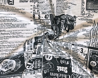 May include: Black and white fabric with a newspaper print design. The fabric features a variety of text, including product names, prices, and advertisements. The fabric is folded in the center, creating a visual interest.