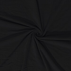 Pode incluir: Uma foto em close-up de tecido preto, enrolado em espiral. O tecido parece macio e drapeia em dobras, com variações sutis na textura e no tom. A impressão geral é de um material escuro e sólido.