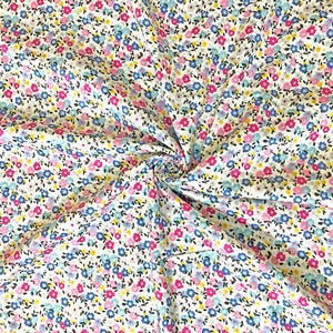May include: White fabric with a small floral print in shades of pink, blue, and yellow.