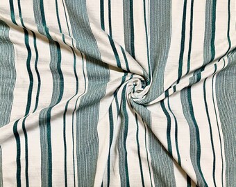 Può includere: Tessuto bianco con strisce verdi verticali. Il tessuto è piegato e attorcigliato.
