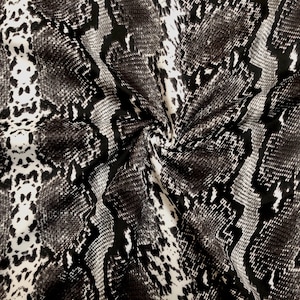 May include: Black and white fabric with a snake skin pattern.
