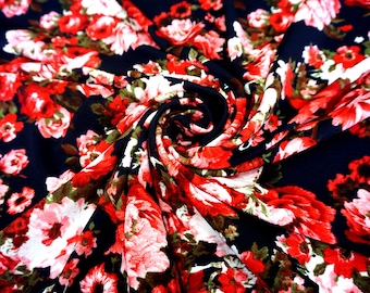 May include: A close-up of a black fabric with a red and white floral print. The fabric is crumpled and has a textured surface.