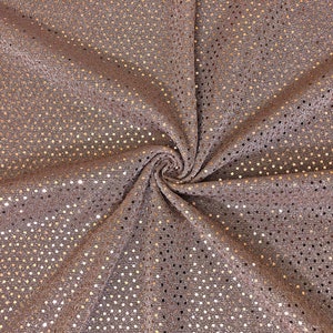 May include: Close-up of a fabric with a textured surface and a pattern of small, evenly spaced holes. The fabric is a muted rose gold colour, with a subtle sheen. The fabric is gathered in a swirl.