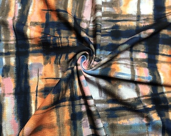 Puede incluir: Tela con diseño abstracto y superficie texturizada. El patrón combina tonos naranja, azul marino, marrón y rosa, evocando una pintura de acuarela. La tela está doblada, revelando los intrincados detalles del diseño.