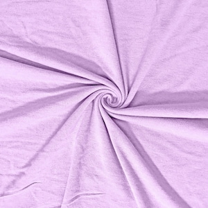 May include: A close-up shot of a light purple fabric with a spiral pattern in the center. The fabric is soft and appears to be made of a knit material. The folds and textures of the fabric create a visually appealing design.