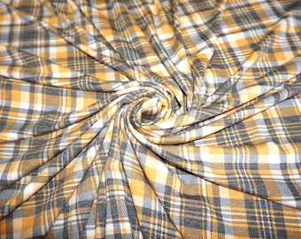 May include: A close-up of a yellow, white, and gray plaid fabric. The fabric is folded and twisted, creating a swirling pattern.