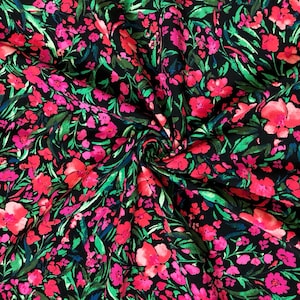 May include: Black fabric with a vibrant floral pattern. The design features bright pink and fuchsia flowers, green leaves, and touches of blue against a dark background. The fabric is likely used for clothing or home decor.