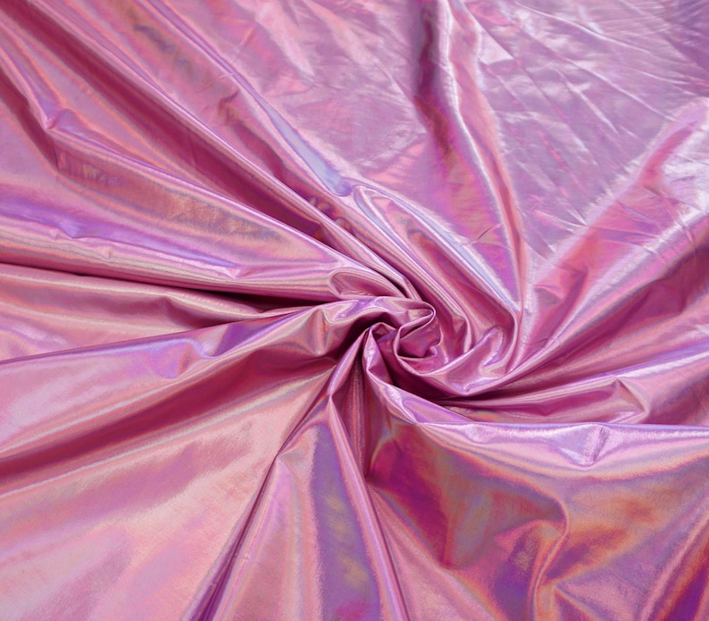May include: Close-up of iridescent pink fabric with a smooth, shiny texture. The fabric is folded and draped, creating a soft, flowing effect.