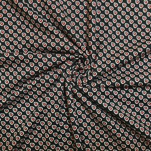 Könnte beinhalten: Schwarzer Stoff mit einem sich wiederholenden Muster aus kleinen roten und weißen Tropfenformen.
