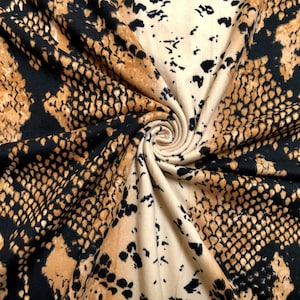 May include: Brown and black fabric with a snake skin pattern. The fabric is folded and twisted.