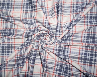 May include: White fabric with a red and blue plaid pattern. The fabric is folded and twisted, creating a swirling effect.
