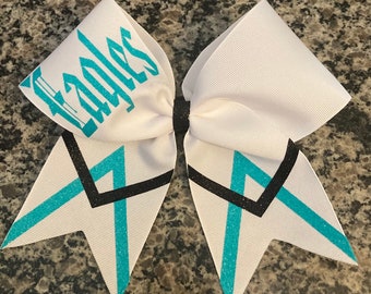 May include: White cheer bow with teal and black glitter accents. The bow has the word "Eagles" written in teal glitter on one side.