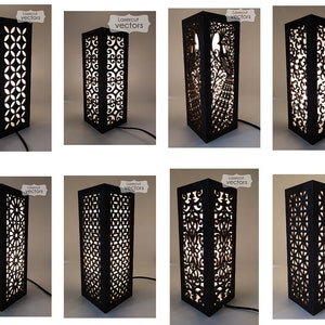 Könnte beinhalten: Acht schwarze Tischlampen aus Holz mit aufwendigen Laser-Schnitten. Die Designs umfassen geometrische Muster, florale Motive und einen Pfau.