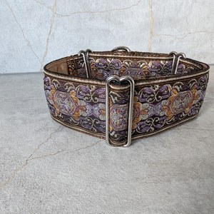 Könnte beinhalten: Ein braunes, violettes und goldenes Hundehalsband mit silberner Beschläge. Das Halsband hat ein Blumenmuster.