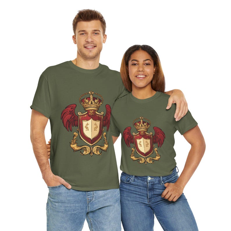 May include: Two olive green t-shirts featuring a detailed crest design. The crest includes a crown, red wings, and a shield with gold accents. The shirts are worn by a man and a woman, both wearing blue jeans.