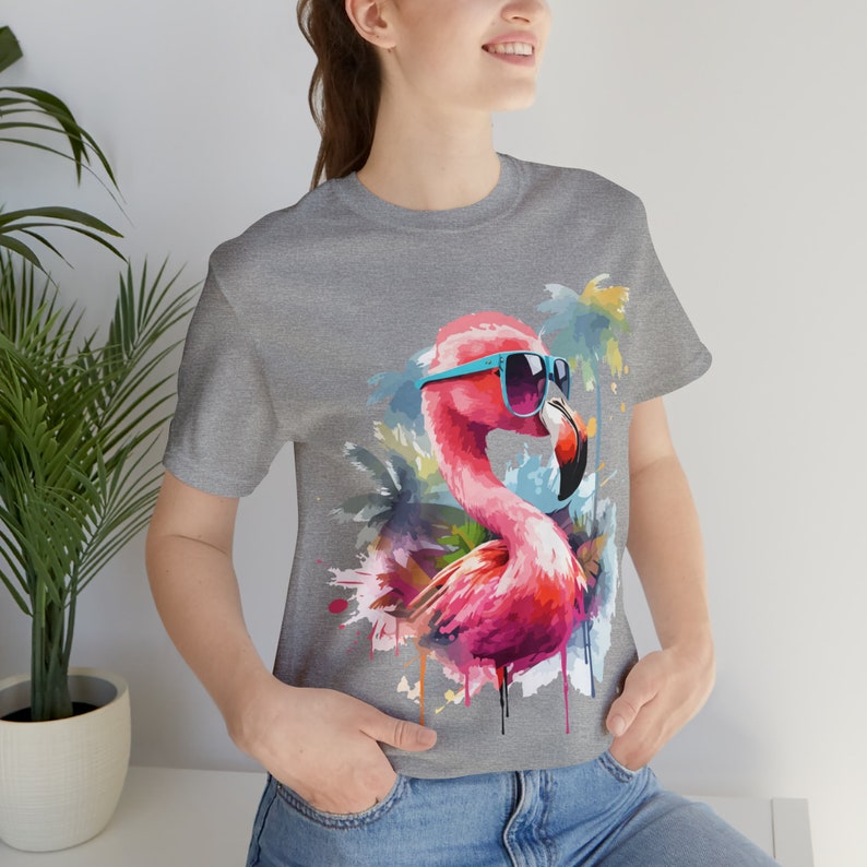 May include: A grey t-shirt with a pink flamingo wearing blue sunglasses and a watercolor background of palm trees.