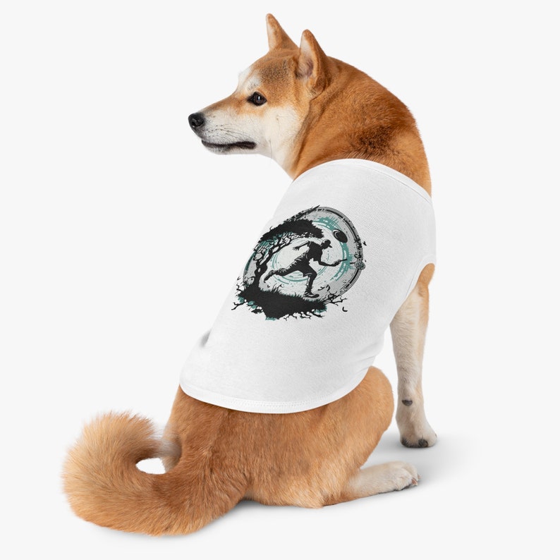 May include: White dog wearing a white tank top with a black and green graphic of a person running in a circle with a tree and a moon.