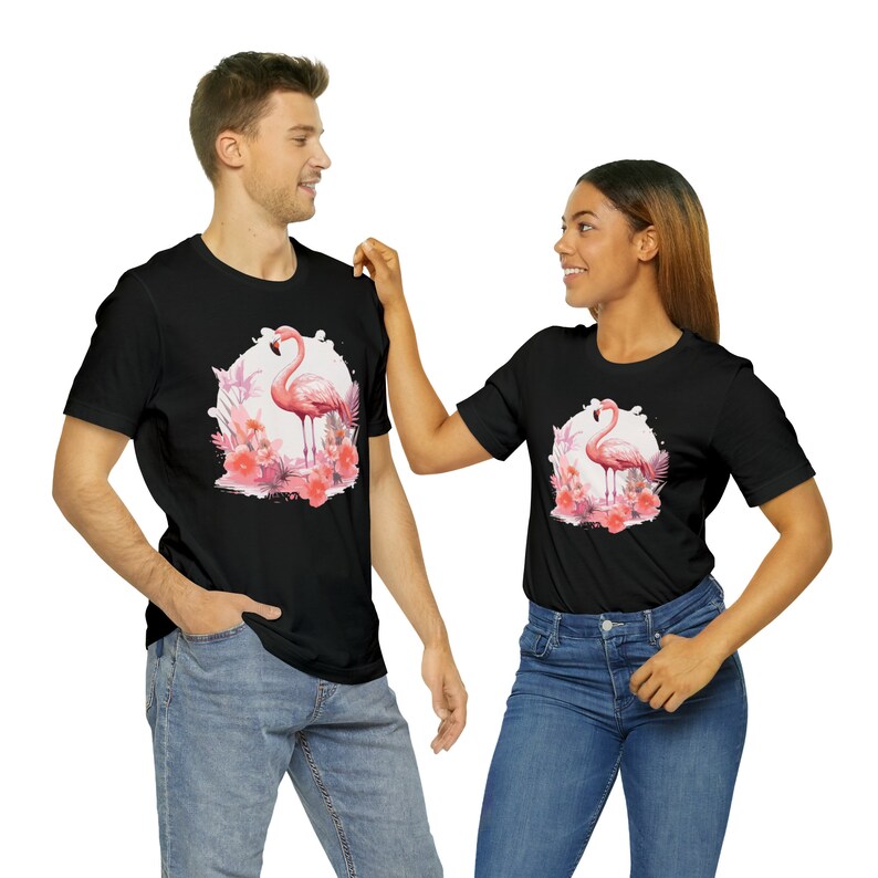 May include: Two black t-shirts with a pink flamingo and tropical flowers graphic print. The shirts are a matching set.