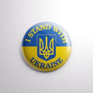 May include: A circular badge in the colours of the Ukrainian flag, blue and yellow. The text "I STAND WITH UKRAINE" is displayed around the edge, with the Ukrainian coat of arms in the centre.