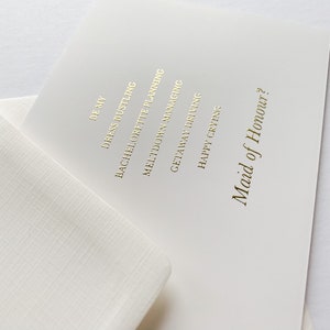 Puede incluir: Una tarjeta blanca con letras doradas que dice "De My Dress Hustling Bachelorette Planning Meltdown Managing Getaway Driving Happy Crying Maid of Honour?"
