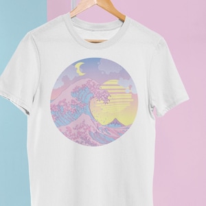 May include: White t-shirt with a pastel pink, blue, and yellow graphic print of a wave, moon, and sun. The graphic is in a circle.