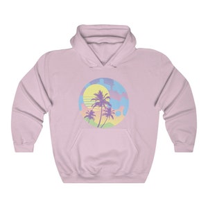 May include: A pink hoodie with a graphic of a sunset with palm trees in a circle. The graphic is in pastel colors of pink, blue, yellow, and green.