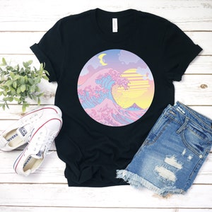 May include: Black t-shirt with a graphic of a pink, blue, and yellow wave with a crescent moon and sun in a circle.
