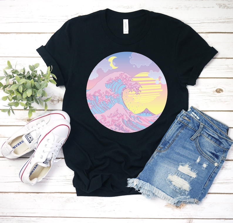 May include: Black t-shirt with a graphic of a pink, blue, and yellow wave with a crescent moon and sun in a circle.