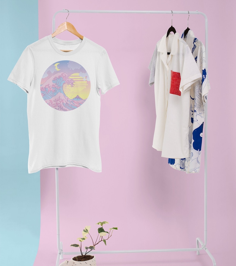 May include: White t-shirt with a pastel pink, blue, and yellow graphic print of a wave, moon, and sun. The graphic is in a circle.