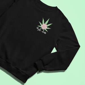 Puede incluir: Sudadera negra con una hoja de marihuana verde y una rosa rosa con el texto "high class" impreso en la parte delantera.