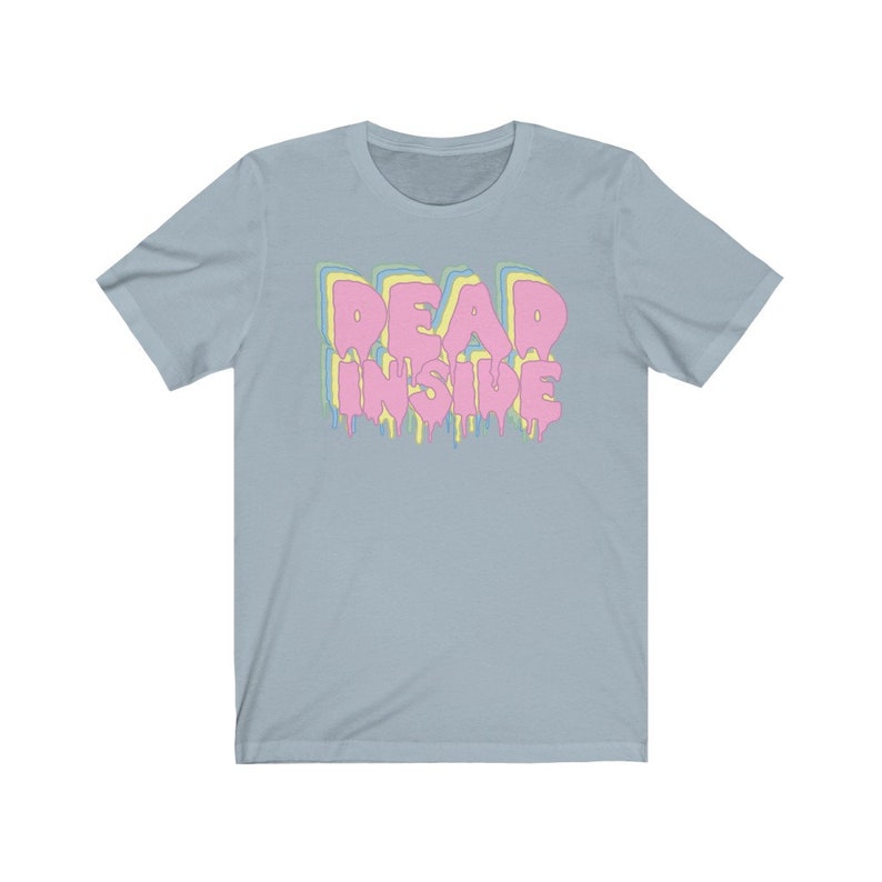 May include: Light blue t-shirt with the text "DEAD INSIDE" in a dripping, layered design. The text is in pink, yellow, and blue. The shirt has short sleeves and a crew neck.