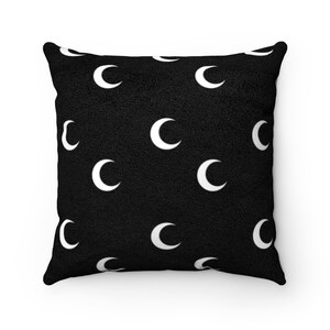 Puede incluir: Almohada negra con un patr&oacute;n de media luna blanca.