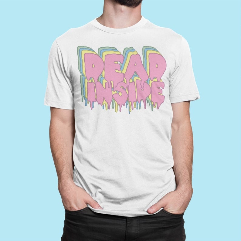 May include: White t-shirt with the text "DEAD INSIDE" in a layered, dripping font. The text is primarily pink, with blue, yellow, and green outlines. The shirt is a casual, unisex style.
