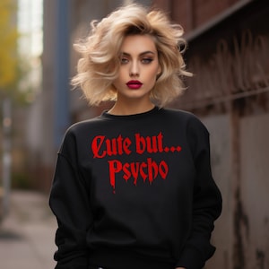 May include: Black sweatshirt with a red graphic print that says "Cute but... Psycho" in a gothic font.