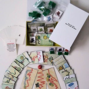 Pu&ograve; includere: Un gioco da tavolo chiamato "Tour du Jour" con biciclette verdi, rosse e blu, un dado e carte da gioco con illustrazioni di strade tortuose. Il gioco include istruzioni su come giocare.