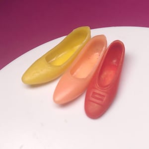 May include: Three miniature shoes made of fondant in yellow, orange, and red.